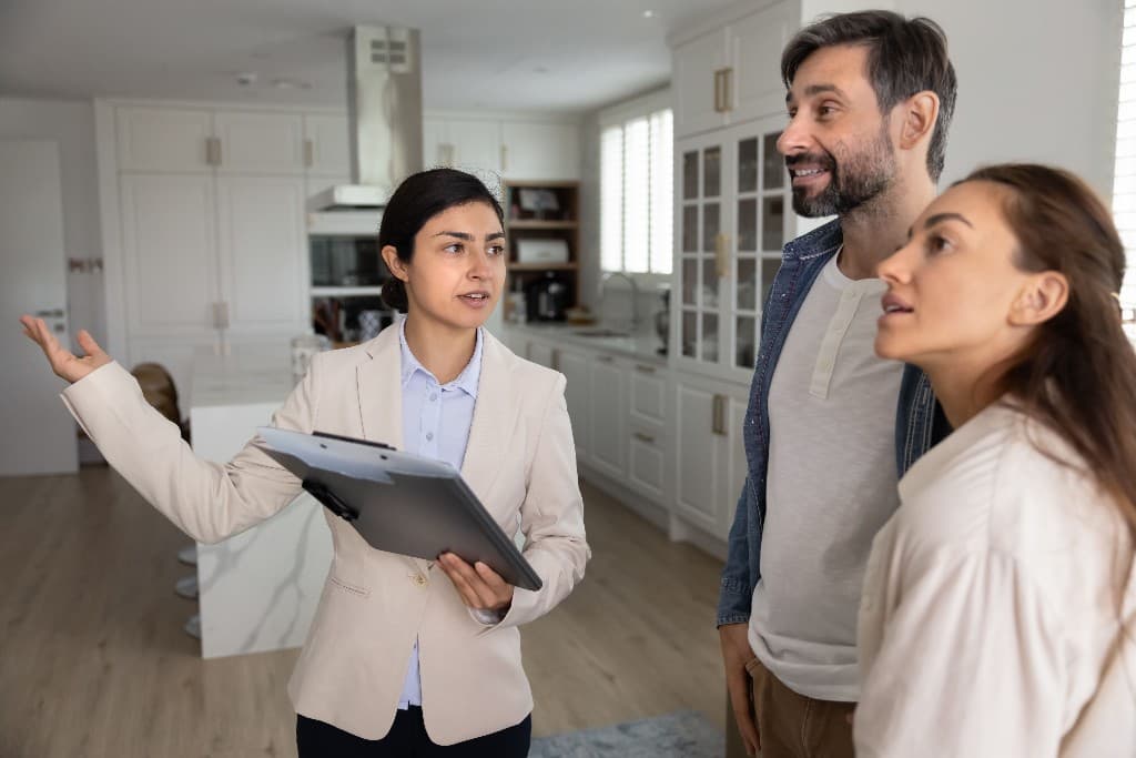 Asesor inmobiliario mostrando un departamento a una pareja interesada